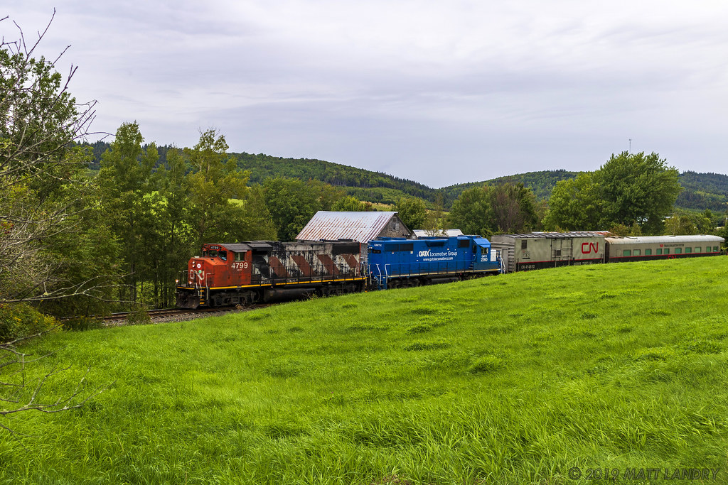 Running as the test train, A406 heads along the countryside of southern New Brunswick, at Norton, with a blue leaser trailing.