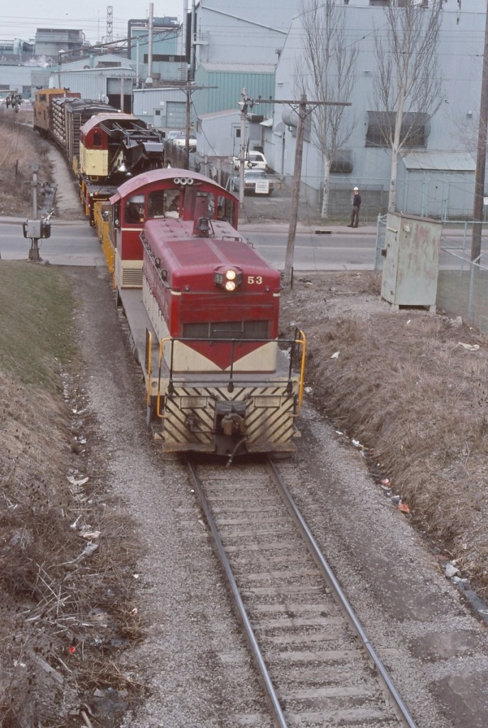 A photo from Ray Hoadley, taken at Beach Rd, Hamilton as TH&B 53 heads up the Belt Line with Industrial Brown Hoist TH&B X-766 in tow as well as a couple of other cars. Ray must have been standing on the embankment of the subway underpass of the CN Grimsby sub. There had been a derailment in the TH&B Adams Yard and the "big hook" had attended to the scene. In the image there is a bulk head flat loaded with cast iron pipes, one of the cars that had derailed.
I recall going through this spot numerous times when I worked for the TH&B. Beach Road was a nasty crossing and mid 1972 a transfer job was heading up the Belt Line and hit a truck at the crossing, killing the driver, some crew members receiving minor injuries and TH&B 56 more or less wedged in the subway overpass.