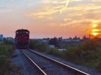 The sun slowly peaks out on what will be a very hot and sunny day in July as CN Local 579 rests at the north end of the 4 mile North Park Spur in Brampton with light power as they await permission to proceed through the busy Brampton Intermodel Yard after having just finished working the Chrysler Assembly Plant. Timing is 05:56am. 