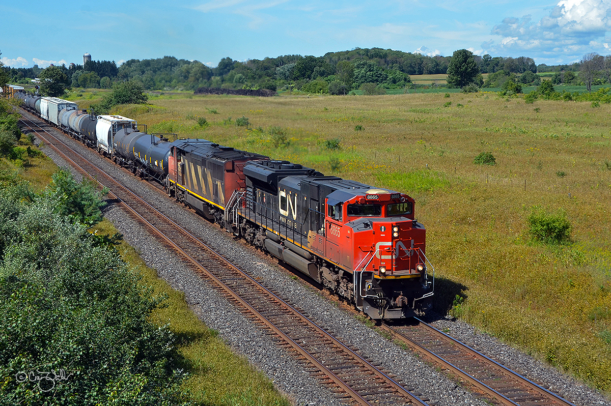 Not far from the shore of Lake Ontario, Canadian National train M37631 passes through bucolic Newtonville, Ontario, on a beautiful late summer day.  Powered by CN SD70M-2 8865 and Dash 8-40CM 2419 (with mid-train unit Dash 8-40CW 2125 [the former Union Pacific 9090, originally Chicago & North Western 8549]), train 376 is heading from Toronto, Ontario's MacMillan Yard to Rivière-des-Prairies, Québec, with a load of merchandise.  (August 25, 2019)