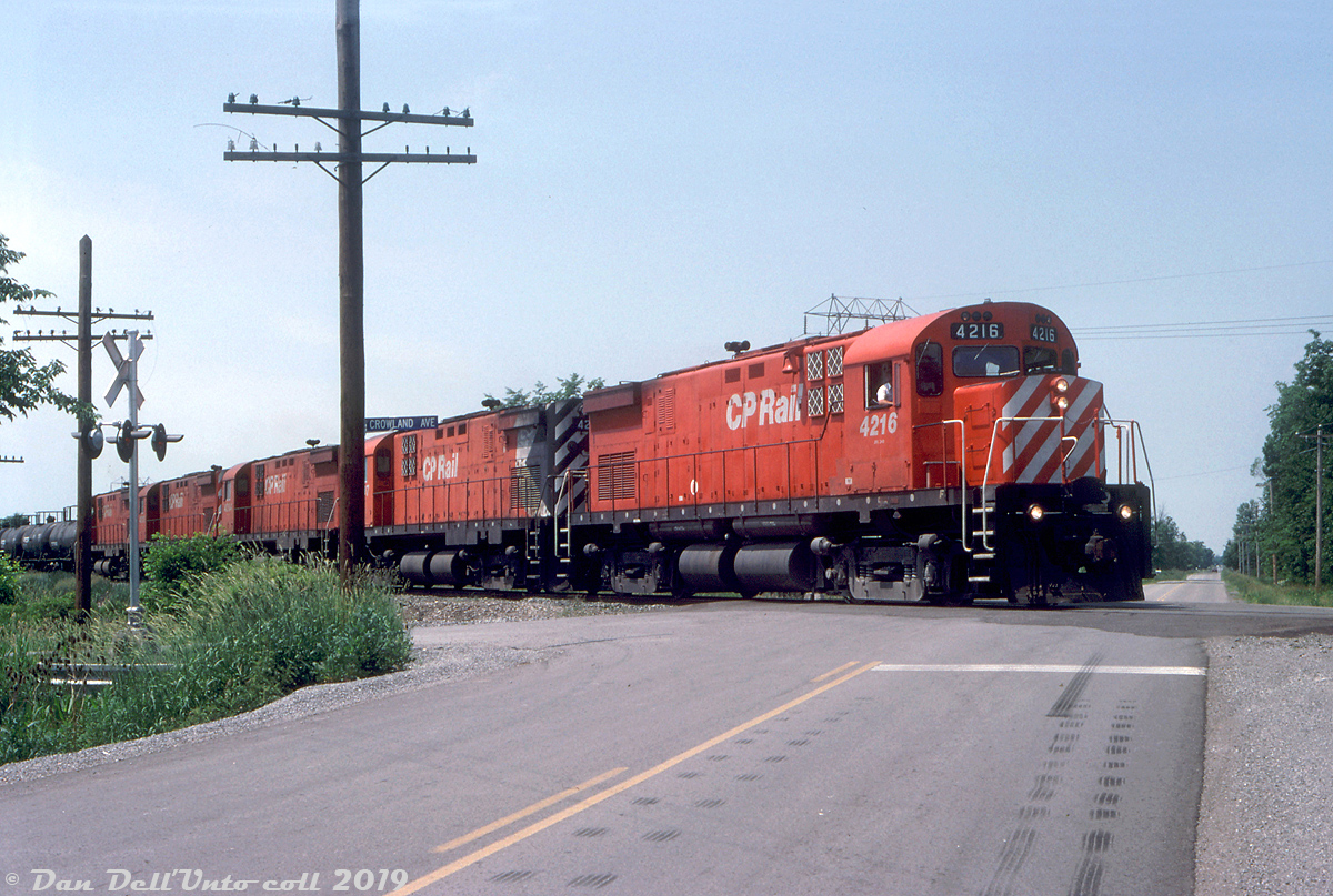 Leaving the climb out of the Welland Canal behind, the five CP C424 "Centuries" from before motor over the double crossing at Crowland Ave. and Biggar Rd. on the former Conrail CASO Sub (that had become CP's Hamilton Sub) as they near Montrose Yard in Niagara Falls with an acid extra. This slide was stamped as the next sequential number after the previous shot at Brookfield, so Reg probably gave chase and managed to get ahead of it here before it arrived at the yard.  Incidentally, this photo by Bill Thomson was taken at the same crossing on the CASO early in the Conrail era, but the train is heading in the opposite direction (having departed Montrose Yard).  Reg Button photo, Dan Dell'Unto collection slide.