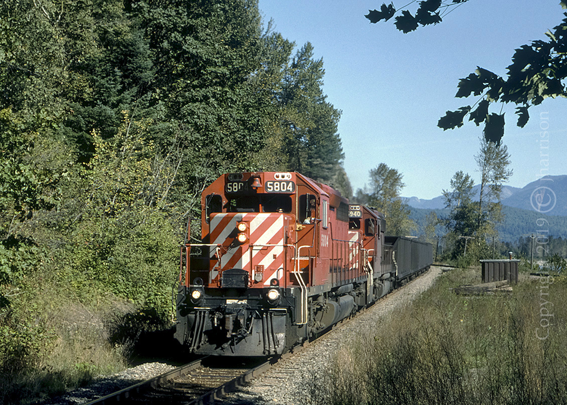 CP 5804 with the 5890 trailing, are about to enter the westward track tunnel with a loaded coal train at Agassiz, on CP's Cascade Sub. With two tunnels side by side at this location, the other track visible in the background was, before directional running began, for eastbound traffic only.