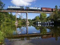 CMQ 1 with matching GE's CEFX 1002/CEFX 1006 and 66 cars is crossing the Eastman trestle on its way to Farnham Yard as the train is reflected in Lac d'Argent on a still morning.