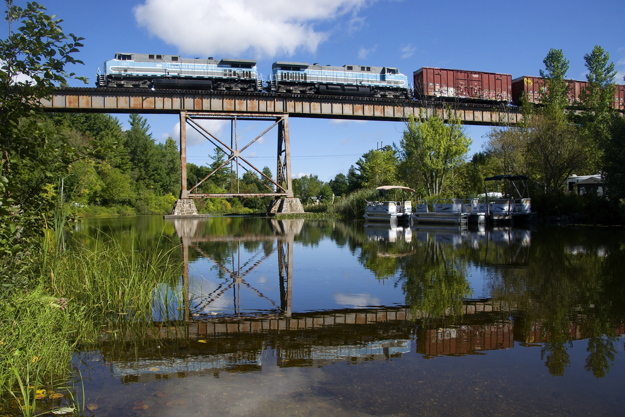 CMQ 1 with matching GE's CEFX 1002/CEFX 1006 and 66 cars is crossing the Eastman trestle on its way to Farnham Yard as the train is reflected in Lac d'Argent on a still morning.