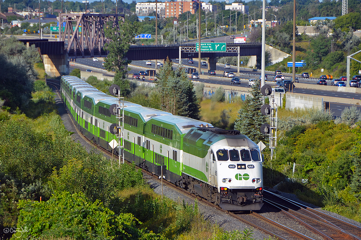 GO Transit train 9204, heading east from Toronto's Union Station to Oshawa, passes through Bayly as it slows for the stop in Pickering.  GOT MP40PH-3C 665 is on the headend of twelve matching commuter cars, all in the "new" paint scheme, which was adopted in 2013 - although, six years later, not all the equipment has been repainted.  The GO train is passing under Canadian National's York Sub, which diverges at Pickering Junction on the Kingston Sub (just to the left out of this photo) and crosses over both the GO Sub and the Ontario 401 Expressway by way of the through truss bridge in the distance, heading for CN's MacMillan Yard in Vaughn, a suburb of Toronto.  (August 25, 2019)
