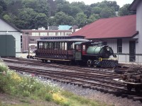 Huntsville and Lake of Bays Railway No. 1, a 1926 MLW coal-fired 3'6'' gauge 0-4-0 saddle tank engine "The Portage Flyer", is posed beside its station in Huntsville, 2 days after the heritage railway officially opened on 1 July 2000. <br><br> Waterways used to be primary transportation corridors in Muskoka. The original route of the narrow gauge railway, completed 1904, portaged the short distance between Lake of Bays and Peninsula Lake - the terrain and 100 foot water level difference making a canal uneconomic. The rail route of just over a mile was also challenging, with steep grades, tight curves and a switchback.<br><br> By 1959 transportation changes had made the railway unprofitable, and it was shut down. The track, engines, and equipment were sold privately and used to build and operate Pinafore Park RR in St Thomas, Ontario.<br> Around 1985 the steam engines (at least) were sold to a group of enthusiasts who were the nucleus of the Huntsville and Lake of Bays Railway Society. <br> In 1993 the H & LoB Railway Society agreed with other organizations to establish Muskoka Heritage Place, with a new 1 km railway route to be built in Huntsville Memorial Park, and the construction of an engine house, station, acquisition/refurbishment of material and equipment, etc. <br><br> More history and background at portageflyer org website, though operational info was outdated. <br> Historic maps and pictures at  railwaypages  the-portage-flyer  and  trainweb oldtimetrains<br> Schedule information is at muskokaheritageplace ca website - I would contact them to verify before visiting.<br> Be aware that diesel locomotive No. 3 powers a lot of their trains. <br> <i>Caption has been revised after comment, thank you.