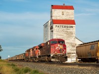 CP 851, 11,000 feet of coal empties from Thunder Bay to Sparwood, is pictured here heading past the old Paterson grain elevator and into the hole at Mortlach where it would have to wait for three eastbounds and one westbound to pass before proceeding onward. They blocked the 'main street' heading north-south in Town and the conductor waited at the crossing in case a car showed up, at which point they'd have to break the train. Once the four other trains cleared, he had to walk the thousands of feet back up to the head end so they could continue heading west. <br><br>The DM&E hopper at right presumably got nailed by the detector and was set off there. There was a lone coal hopper sitting in the area too.