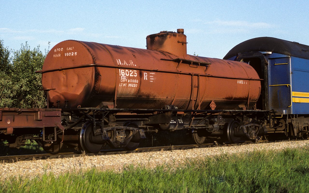 A recent post brought to mind this photo I took back in 1986. I think the time was around 20:00 on this evening when the Mixed train passed through Redwater. It was this car next to the coaches that sent me out to take pictures (besides the sun being out :-) ). On a few occasions, old cars like this were sent north to serve some purpose. I also noted on a couple of occasions, when returning home, some of these cars ended up at the car recycling facility, located just north of Edmonton on the Coronado Sub. I did check, not deeply extensive but looked, could not find any info for some history. The word FUEL is probably what the car was still being used for. Of interest, on the leading wheel, on the rear truck, the side of the wheel next to the axle can be seen. Looking carefully, you can see it has the curved fins to aid in cooling. Tonight's Muskeg Mixed consisted of 5585 and 5580 (GP38's) up front, behind tank 16025 is baggage cars 7855 and 7856 with coach 5099 and ex-NAR caboose 79101. Shot at mile 34. One last oddity, the flat car and tank 16025 both have upright brake wheels, don't see that to often anymore.
