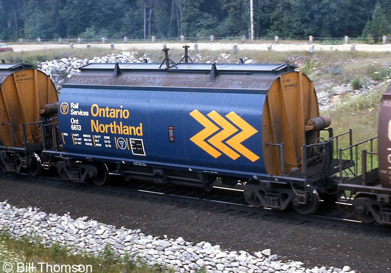Ontario Northland ore hopper 6613 is seen on a CN unit ore train heading through "Mile 30" near Milton in July 1974. This car was part of a group of 61 NSC-built 3712cuft cylindrical covered hoppers built in 1973-1976 for service hauling pelletized ore in unit trains from Bruce Lake, Ontario. CN had 201 cars of the same design they also pooled with ONR for this service.

There were also 35 earlier (slightly shorter) cars of this design numbered in the ONT 6500-series, built in 1967 for ore train service from Temagami with similar CN cars.

Another ore train photo: http://www.railpictures.ca/?attachment_id=18066.