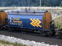 Ontario Northland ore hopper 6613 is seen on a CN unit ore train heading through "Mile 30" near Milton in July 1974. This car was part of a group of 61 NSC-built 3712cuft cylindrical covered hoppers built in 1973-1976 for service hauling pelletized ore in unit trains from Bruce Lake, Ontario. CN had 201 cars of the same design they also pooled with ONR for this service. Note the wheels attached to roof hatches that contacted an overhead rail and allowed the hatches to be opened and closed automatically before and after loading.<br><br>There were also 35 earlier (slightly shorter) cars of this design numbered in the ONT 6500-series, built in 1967 for ore train service from Temagami with similar CN cars.<br><br>Another ore train photo: <a href=http://www.railpictures.ca/?attachment_id=18066><b>http://www.railpictures.ca/?attachment_id=18066</b></a>.