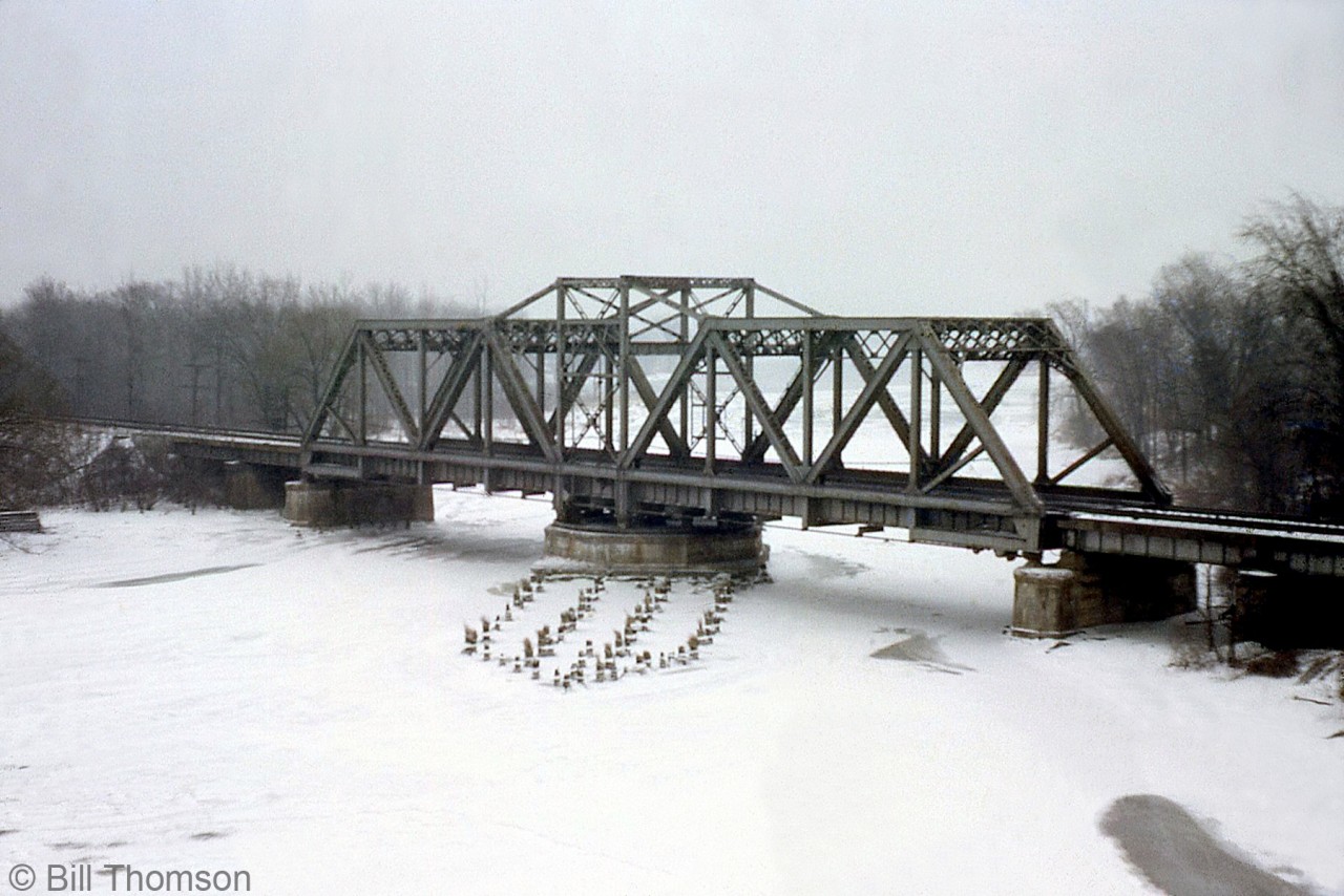 The steel swing bridge carrying Penn Central's CASO Sub (ex-Michigan Central) over the Welland River at Montrose is pictured, as viewed from the nearby Queen Elizabeth Way on a gloomy day in 1967.

At the time of this photo, this portion of the CASO ran straight from Niagara Falls to Welland. Due to the Welland By-Pass project, it wouldn't be long before a portion of the line to the west was diverted south on a new alignment via Brookfield to the new Townline Tunnel running under the Welland Canal. This bridge and portion of the line still see rail traffic today (but far less volume), as this part of the CASO became CP's Hamilton Sub in the 1980's, and later CP's Montrose Sub.