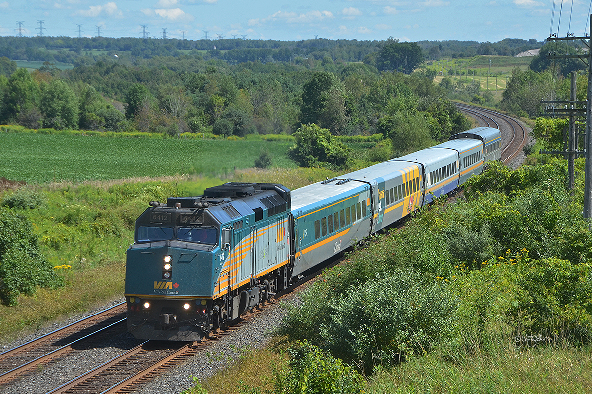 Leading four LRC cars and a stainless steel coach, VIA Rail Canada F40PH-3 6412 and its train (VIA 643, a weekend service Corridor train heading from the capital of Ottowa to Toronto) passes through Newtonville, Ontario, on August 25, 2019.