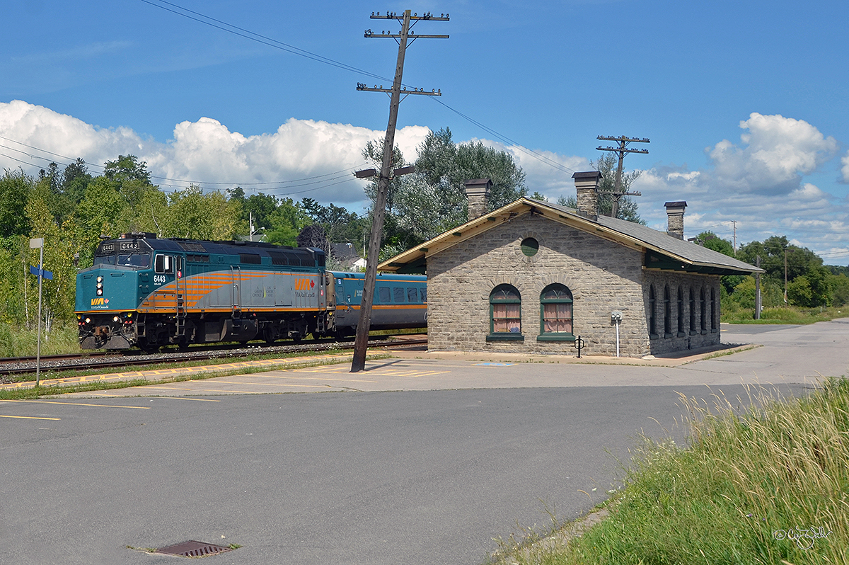 Passing one of the oldest Canadian passenger rail stations still in active use, VIA Rail Canada train 45 heads west through Port Hope, Ontario, heading to Toronto from Ottowa.  Built from local limestone by the Grand Trunk Railway — one of the Canadian National predecessors — this station opened on October 27, 1856 (upon the inauguration of Montréal–Toronto mainline service).  This train, comprised of LRC coaches and powered by VIA F40PH-3 6439, is one that bypasses stopping in Port Hope (the station for which is no longer staffed, although it does have a heated waiting room and restrooms).  (August 25, 2019)