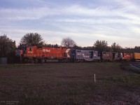 Big MLW-ALCo CP 4709 leads a pair of Ontario-based Conrail (PC) GP9's, RS10 CP 8477, and train close to sunset. <br> The first piggyback trailer has the Conklin Shows clown face logo (CNE midway, etc).<br><br>
Clues to the location are signs "Yard Limits" and "End CTC", a dwarf signal, and the elevated right-side background.<br>
Some experienced Hamilton railfans told me it looks like the "Starlight" train, facing toward Toronto, at the (north) east yard limit of Aberdeen. In which case, the diverging track at right could lead to the Chatham Street roundhouse area.