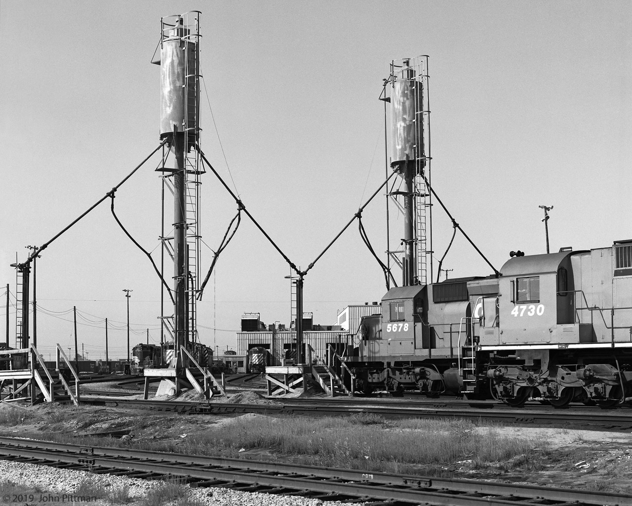 CP's Toronto Yard locomotive sand refill area more than 40 years ago, before it was modernized.
SD40-2 CP 5678 is in position for filling the front sandbox, while M636 CP 4730 is nearby.
In the background, left to right, are TH&B 77, CP 5731, CP 5537, with CP 4705 inside the diesel shop.
The official name of the diesel shop as of 2019 appears to be Locomotive Reliability Centre, based on signage visible from Finch Ave bridge.