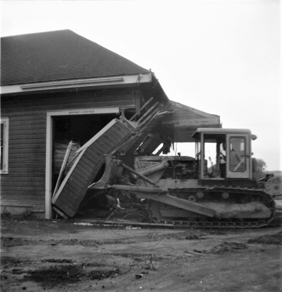 On the morning of Tuesday, August 31st, 1965, after westbound freight 401 passed, crews went to work to erase the old wood frame CN Pembroke Ontario station from the planet. The west wall of the building was the first to go.  This photograph shows one of the first blows being administered. As the entire structure was deemed as scrap, no effort was made to save anything. The process took only about a hour. Location is approximate.