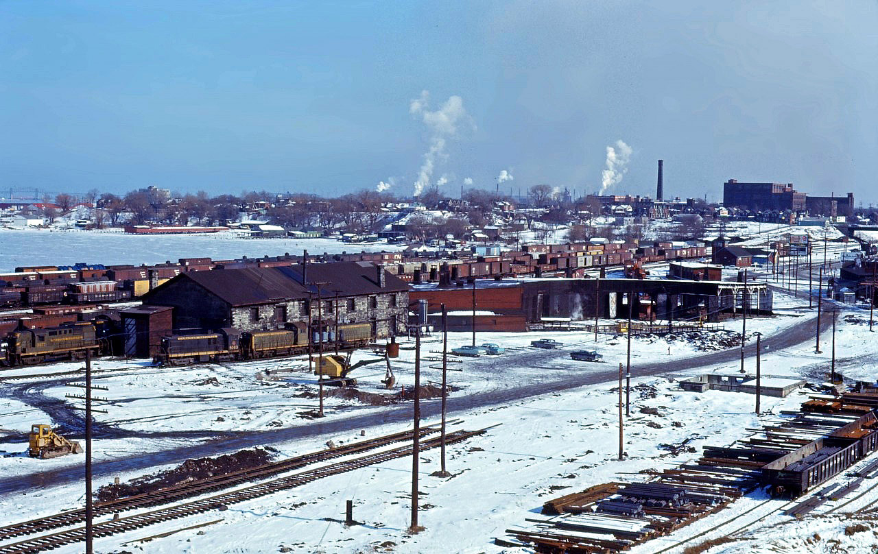 In the year 1964, CN's facilities in Hamilton received a major modernization, with the construction of a new Diesel shop and Express building/Carload Centre. In this view from early 1964, we see the Great Western era steam facilities which were demolished later that spring; beyond the roundhouse you can see the old Yardmaster's tower. Visible in the photo are two MLW S4 locomotives (8163 and an unidentified unit), two SW1200RS units (1316 and another unit), and RS18 3677.