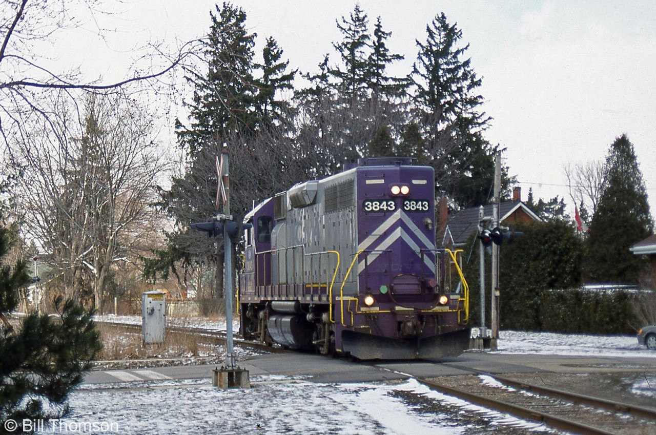 GEXR GP38 3843 runs solo long-hood forward, seen crossing Aberdeen Street heading towards Paisley Street on the Guelph North Spur during March 2002. 3843 originally operated for the L&N, Seaboard and CSX before being sold to the North Carolina and Virginia Railroad (NCVA), where it acquired its purple and silver paint scheme. The colours earned it the nickname of "Barney", but the unit left the GEXR when it was sent to the New England Central in 2006.