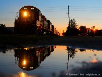 Sailor's delight is predicted by the glowing orange sky, battle hardened GP9 7071 is reflected in a small puddle as the Conductor throws a switch to turn south and head home. Leaving the Guelph Junction railway, this weekend extra will head south on the old Fergus sub then turn west following the orange glow home for the night to Kitchener.