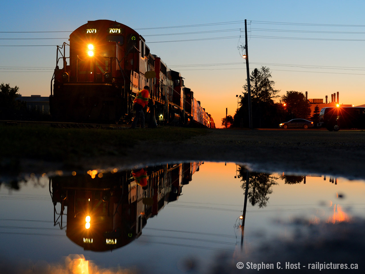 Sailor's delight is predicted by the glowing orange sky, battle hardened GP9 7071 is reflected in a small puddle as the Conductor throws a switch to turn south and head home. Leaving the Guelph Junction railway, this weekend extra will head south on the old Fergus sub then turn west following the orange glow home for the night to Kitchener. 

Note to snake: my family was at *WAL MART* nearby and I chanced on the train that evening :) Guess what they were buying???