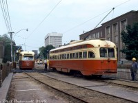 TTC A6-class PCC 4363, operating westbound on the Carlton route, pauses to talk to the operator of eastbound PCC 4707 (an A13-class ex-Birmingham car) near the corner of College Street and St. George Street on the Canada Day weekend of July 1972. Both cars are operating on temporary diversion tracks laid on the south side (eastbound lanes) of College, due to a road cave-in (note the excavator working in the background). Temporary tracks or "shoeflies" were often used by the TTC to keep streetcars operating over a road when construction was going on, or as an alternative to diverting the route down adjacent roadways. The University of Toronto's Wallberg Memorial building is visible on the right.
<br><br>
<i>Robert D. McMann photo, Dan Dell'Unto collection.</i>