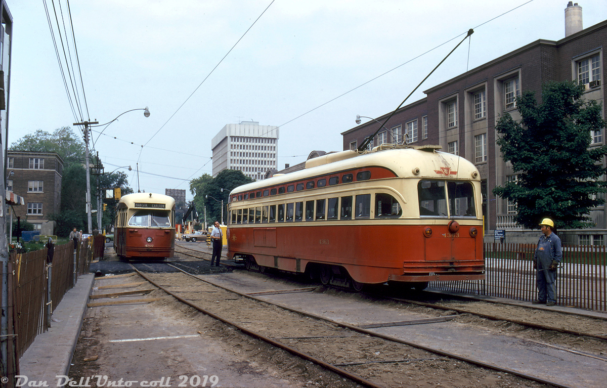 TTC A6-class PCC 4363, operating westbound on the Carlton route, pauses to talk to the operator of eastbound PCC 4707 (an A13-class ex-Birmingham car) near the corner of College Street and St. George Street on the Canada Day weekend of July 1972. Both cars are operating on temporary diversion tracks laid on the south side (eastbound lanes) of College, due to a road cave-in (note the excavator working in the background). Temporary tracks or "shoeflies" were often used by the TTC to keep streetcars operating over a road when construction was going on, or as an alternative to diverting the route down adjacent roadways. The University of Toronto's Wallberg Memorial building is visible on the right.

Robert D. McMann photo, Dan Dell'Unto collection.