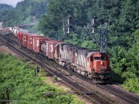 A morning CN eastbound powered by a pair of MLW C630m locos enters CN's Oakville Sub off the Dundas at CN Bayview.<br>
CN 2028 and CN 2029 lead the train - the flatcar load 6 cars back looks agricultural, could be a combine harvester.<br><br>
Of interest beside the south track are active lineside wires and poles, a CN telephone, and a pair of light rails perpendicular to the track - presumably to park a speeder.<br>
The Hamilton/Burlington boundary is approximately where the engines are. 