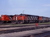 Reg Button got this line-up of 3 MLW and Bombardier locomotives on a sunny June 1983 day at Fort Erie.<br>
Bombardier HR616 CN 2111, MLW C630 CN 2017, and MLW M636 CN 2323 make up the first row.<br>
GMDD power visible in further rows include GP40-2LW CN 9515, and GP9 CN 4590 in fresh diagonal stripes paint.