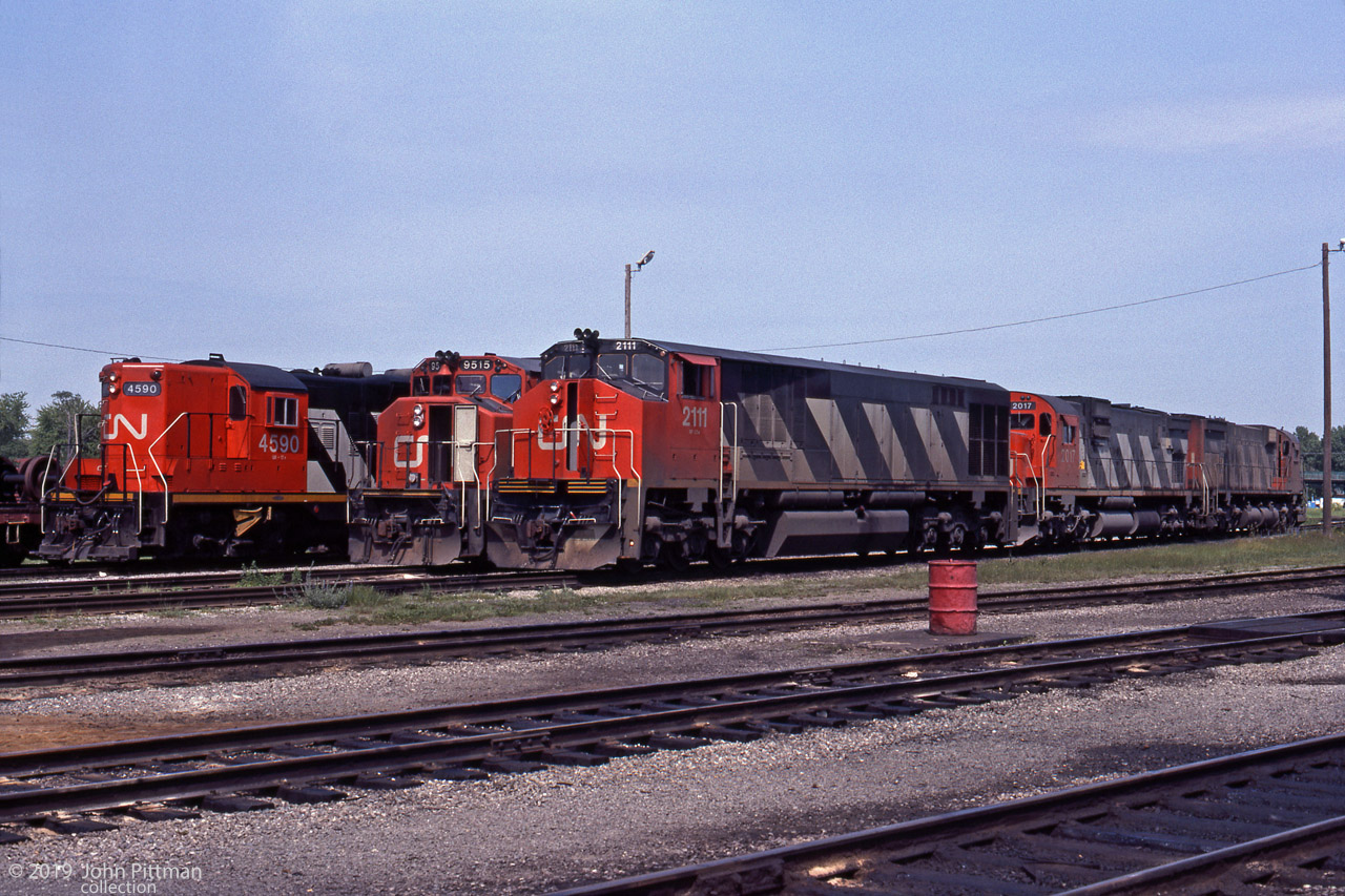 Reg Button got this line-up of 3 MLW and Bombardier locomotives on a sunny June 1983 day at Fort Erie.
Bombardier HR616 CN 2111, MLW C630 CN 2017, and MLW M636 CN 2323 make up the first row.
GMDD power visible in further rows include GP40-2LW CN 9515, and GP9 CN 4590 in fresh diagonal stripes paint.