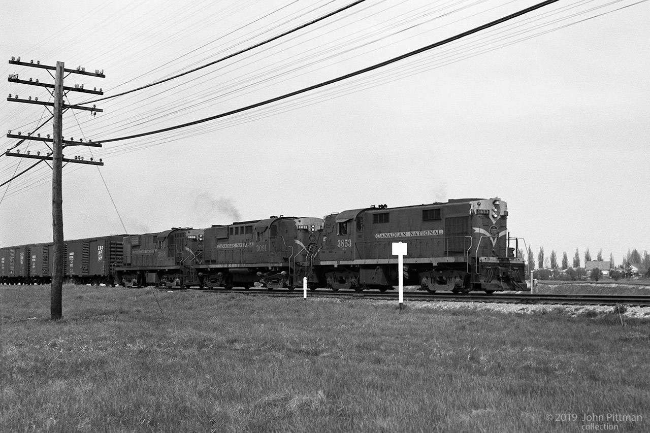 Two MLW RS-18 locomotives built 1960 or 59, with an RS-10 built 1955 between them, lead a train with 40 foot boxcars.
Locos and cars in this image all wear the CN leaf scheme, the locos in olive green with yellow/gold accents.
Several B-B road switchers of 1800 HP or less and a train of mostly boxcars seems to be typical of the era.
Location mapped is approximate.