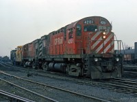 A pair of CP MLW C424's works in Aberdeen Yard with a TH&B Angus caboose and a (Jordan?) spreader/flanger.<br>
Further back in the siding are side-dump cars loaded with dark-colour material to build up the ballast.<br>
A fair amount of this material has already been dumped and spread. Some siding tracks look wavy. <br><br>
Within a couple of months CP would take full control of the TH&B, ending its separate existence.<br>
Location mapped is approximate, assumes east end of yard.

