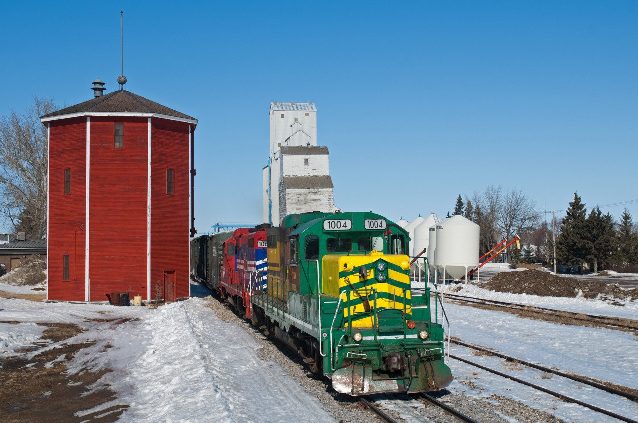 Carlton Trail Railway makes its way south through Hague SK on the line between Prince Albert and Saskatoon. While the brilliant CN water tower can still be seen today, the same unfortunately can not be said about the grain elevator in the background.