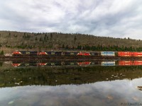 On a calm, cool Fall morning, train 120 crests the climb at Folly Mountain, seen here passing the still waters of Folly Lake, Nova Scotia.