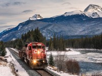 Behind the blue Rockies the sun is declining as a lone SD40-2 hustles along the banks of the Bow River with a single gondola for Eldon.