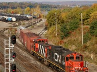 For years CN’s 7200 series GP9RM’s toiled away deep in the large yards across CN’s system, often assigned to the hump yards and typically mated to a slug. Times have changed and with larger power now working those jobs many of these units are beginning to wander elsewhere. CN 7230 has now lost its slug and gained ditch lights. The unit along with relatively rare GMD1 1437 are see busy working Hamilton yard with changing fall colours in the background. 