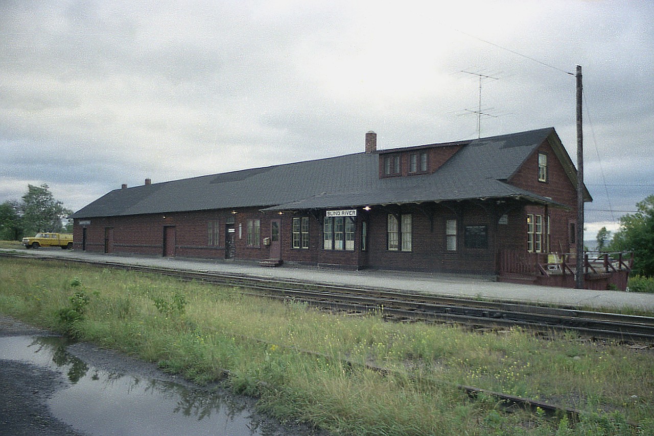 To me, overcast days up north always feel worse than they do down in Southern Ontario. Throw in heavy skies and a dilapidated old CP station slathered with insulbrick and it appears even worse.
Quite the station at Blind River. Rather massive, with a lot of freight area. I would assume to agent lived downstairs for the most part at the right side in this view (note TV antenna). Much too big to move and likely impossible to heat,  this structure was demolished, probably in the early 1980s.
