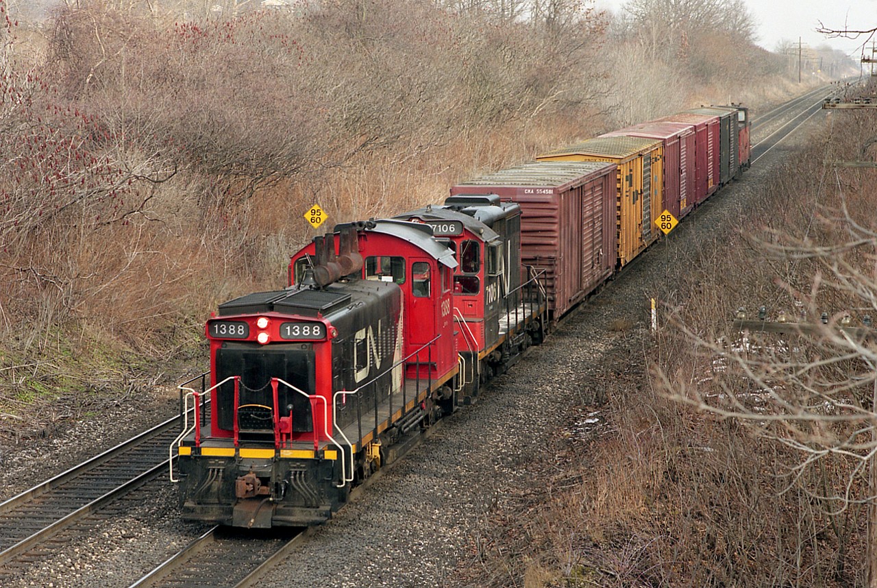 One thing I really miss is the small-time transfers we used to see so many of around the Burlington-Hamilton area. The big freights with their repetitious ACs seem so impersonal.
Hamilton-bound down the grade toward Bayview, on approach to the old Snake Rd bridge is one of those little wayfreights; the once-common SW1200RS, this one #1388, followed by a rather rare (only 8 built) Sweep 7106 with 5 boxcars and a van in tow.
The "Sweep" is actually a  thingumabob resulting from the mating of an SW1200 with a GP. The 8 in total were of GMD/CN  remanufacture in 1985-87 and retired by 2000.