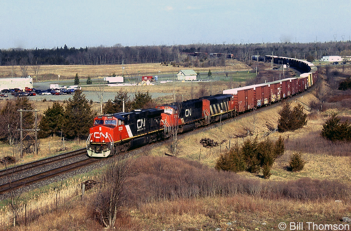 CN ES44DC 2233 leads two other units on eastbound train 360 at Mile 187 of CN's Kingston Sub, passing over 
the County Road 6 crossing in Amherstview, Ontario (just west of Kingston).