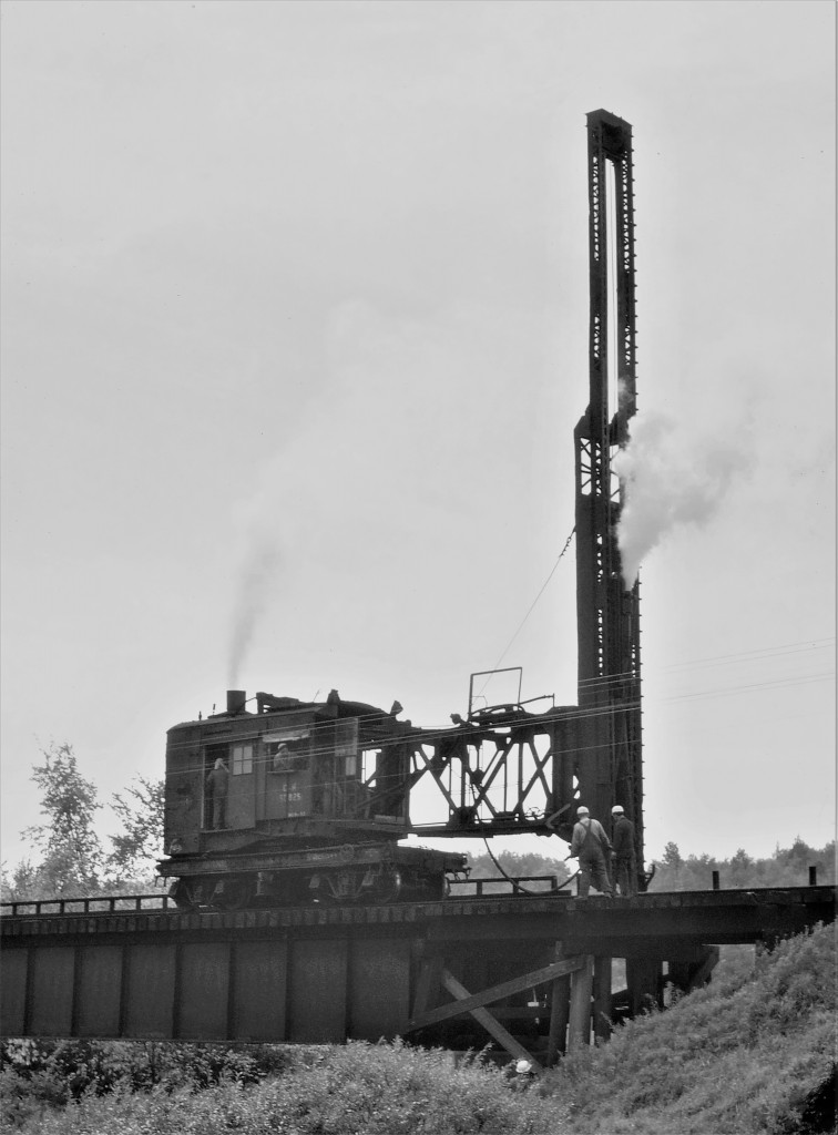 CN steam pile driver 50825 is shown in action pounding away at the west end of the bridge at Field, Ontario.  Notice that there is a five man crew: two on the pile driver itself, two on top of the bridge, and one almost under the bridge making sure the support is placed where it is needed.  KaThump KaThump KaThump  great sounds and all the smells were just a bonus!