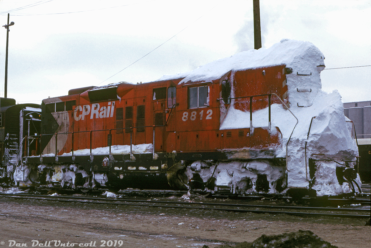 This little Geep probably has an interesting story to tell about its last assignment: CP GP9 8812 sits at Alyth Yard with her pilot, stepwells, and front walkway packed hard with snow, which is also coating the front of her nose up to the roof, and piled up on top of her short hood and cab roof. Perhaps the aftermath of hitting some deep cuts or driftbusting plowed-over grade crossings at speed along some sleepy unplowed branchline out of Calgary working a local (if it had been on a plow run, there would be traces of a power cable for the plow running from the snowed-over 74 volt plug between the grab irons halfway up the nose). It appears the crew elected to de-train out the back of the cab and rear steps, rather than dealing with shoveling their way out the front.

Doug Wingfield photo, Dan Dell'Unto collection.
