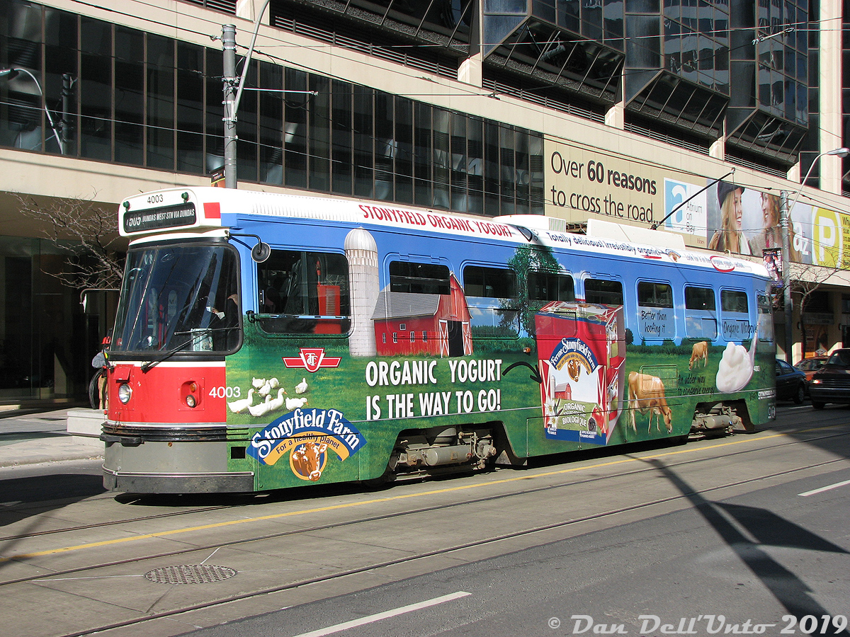 Sporting a brightly coloured advertising wrap for Stonyfield Farm Organic Yogurt, TTC CLRV 4003 pauses to load passengers at the corner of Dundas Street and Bay in downtown Toronto, enroute to Dundas West Station in the Junction area. 4003 was one of the original six Swiss-built SIG CLRV streetcars (cars 4000-4005), which preceded the regular Canadian-built production CLRV's built by Hawker Siddeley/UTDC (4010-4199).Nearly 10 years have passed since this photo, and the aging CLRV fleet that dates from the late 70's have managed to hang on longer than most have expected. There had been plans in the works years ago for a CLRV rebuild program, but that was nixed in favour of buying all-new replacement low-floor accessible cars, which were supposed to arrive much sooner and replace the CLRV fleet. When delivery delays and quality control issues arose with the new Bombardier LRV cars and delayed the TTC's replacement schedule, much of the CLRV (and ALRV) fleet was kept going longer than planned despite age-related reliability issues and cold weather breakdowns.  The final few CLRV's are expected to be retired by the end of 2019, but a few have managed to elude the scrapper's torches and ended up in museums. Car 4003 here (one of the six SIG cars), along with 4010 (the first HSC/UTDC Canadian-built car), 4039 and articulated ALRV 4204 have all been preserved at the Halton County Railway Museum in Milton. Car 4034 has been donated to the Illinois Railway Museum in the US (a relatively modern streetcar addition to their collection). The TTC has retained ALRV 4207, and it is expected that they will keep one, two or three CLRV's of their own when the final cars retire.