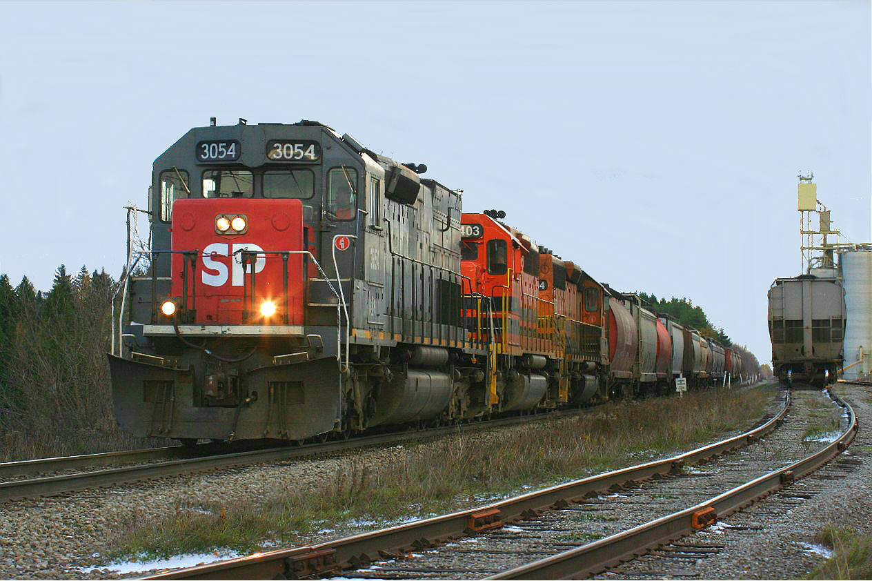 That afternoon I was already rushing around trying to get things packed and organized for a pending dinner with friends north of Toronto in Aurora when a certain someone called. He explained that GEXR 3054 is now back to Southern Pacific 3054. With the previously mentioned commitment pressing there was no time for the who, what, how and why questions to be asked over the phone. It was quite simply load the family in the car and hopefully intersect this train on the way to Aurora. Hearing scanner chatter of 431 switching east of Kithchener meant the train was likely at Shantz working the Parrish & Heimbecker (P&H) facility. So we headed east, and upon arrival there was little time to waste as 431 was already slowly departing after completing its work. After frantically working my way up the well worn path to the tracks above and with literally seconds to work with, I was able to photograph 3054 with it's newly applied SP logo. As a side note, I found out after that when the crew on 432 reported for duty that morning at Stratford, the SP paint was still wet, so it had been very recently done overnight. As well, this would become the last GEXR 431 I ever photographed as the changeover back to CN was less than a week away.