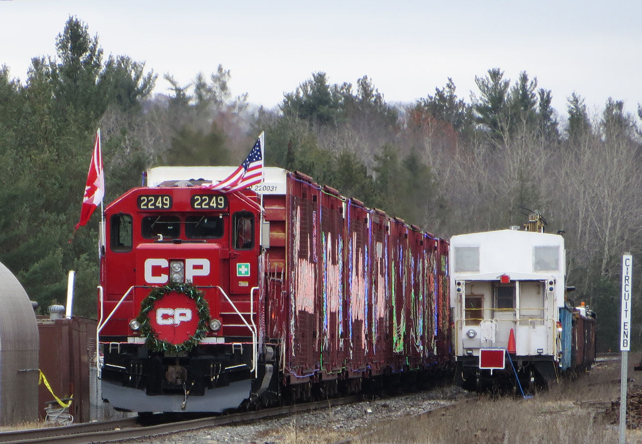 The holiday train rests during the mid day show at Midhurst. On the right tie removal equipment is parked on the spur that was once the siding.