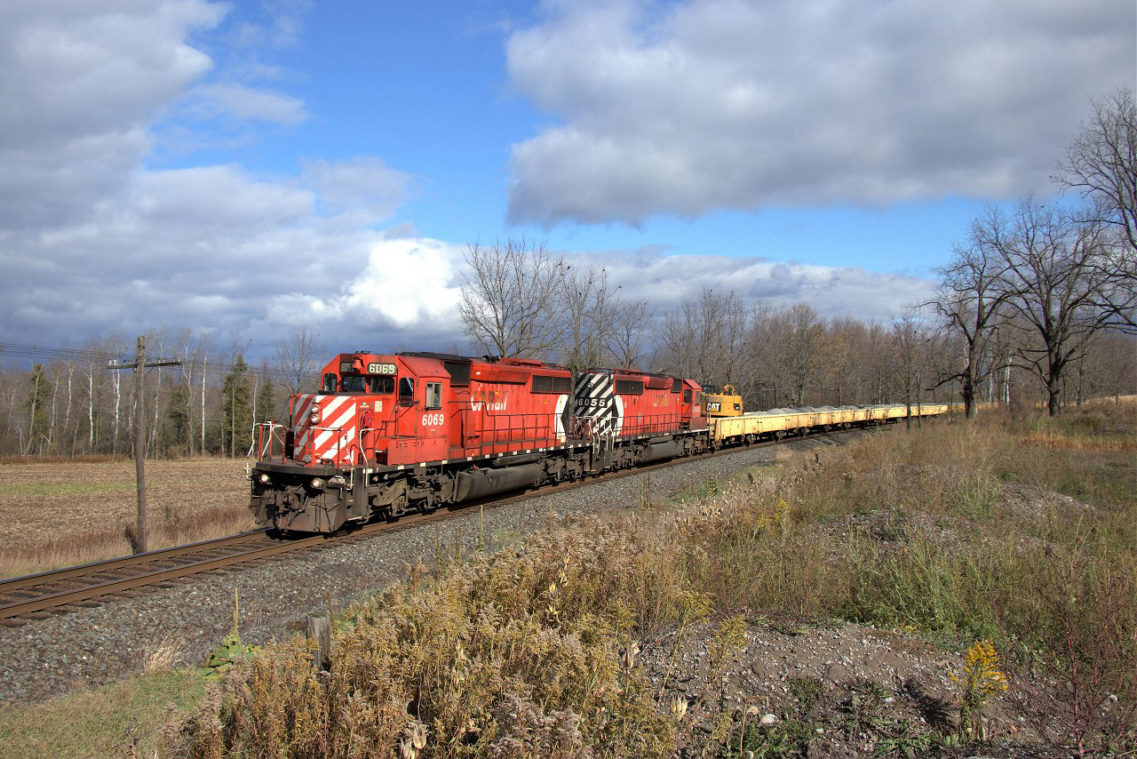 I was really waiting for an eastbound to be called out, and through some static I thought I heard CP 6069 but thought, Nah it can't be true but just to be sure I took off for Victoria Road and ran to this location. My phone rings and it's confirmed. It's darn cold in this field at zero Celsius according to the CP detector but the wait was worth it. To put a bow on this, the clouds parted and the sun came out.
The pair of SD40-2's in CP 6069 and CP 6055 lead the ballast train  up to Victoria Road.