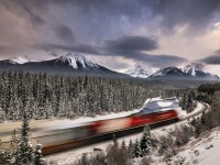 Racing along the banks of the Bow River under a dramatic sky, westbound Canadian Pacific intermodal train no. 101 glides through the iconic, and world-renowned location known as Morant's Curve on the approach to Lake Louise, Alberta.