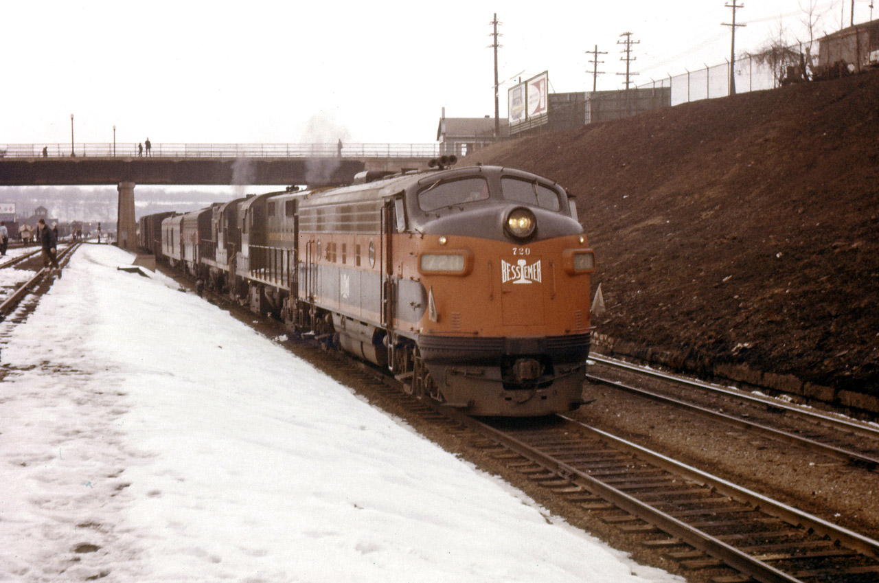 A freight passes the Hamilton station eastbound to the Grimsby sub behind a pair of leased Bessemer & Lake Erie F7As and a pair of CN RS18s. The crowds on the station platforms are there for a Toronto-Guelph-Galt-Hamilton-Toronto excursion behind the 6167.