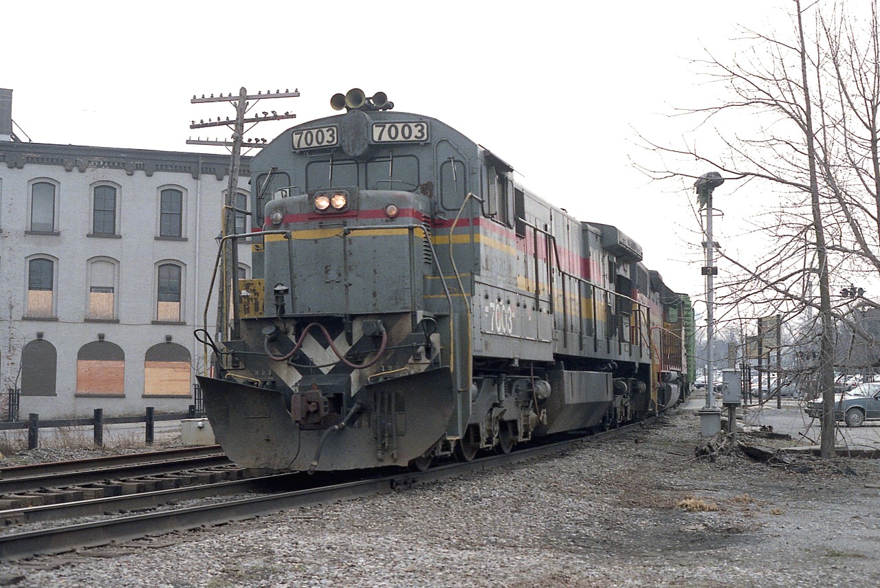 Here's an all-around Grey Day.  I'm good at being stuck with cloudy days but this is a bit ridiculous. Not much in this scene that isn't grey. Thats a 'chessie-cat' scheme barely noticeable on the #2125 trailing leader CSXT (as stenciled on cab)decked in its mostly grey Seaboard Coast Line paint. The ballast is grey, likewise the sky.
It is one of those days. Even the old King Eddie hotel on the left, living out its last months, is a coat of grey paint, accented by boarded up windows as it awaits the wrecking ball. The setting for this eastbound is at Queen St in the Falls; not exactly a classy part of town either. Colour it grey.