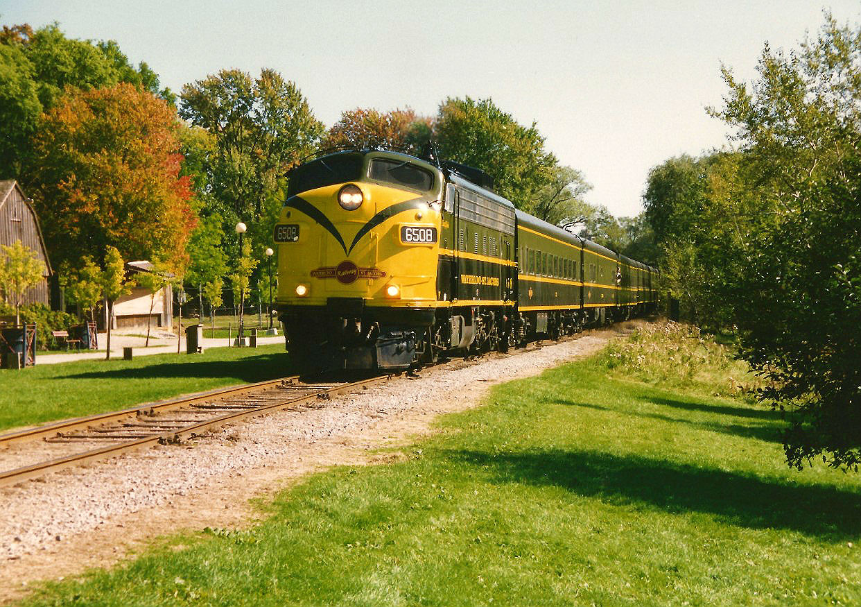 More than twenty years ago during a much simpler time and prior to the creation of the light rail network, Waterloo-St. Jacobs Railway (WSJR) 6508 leads a northbound excursion through Waterloo Park on the CN Waterloo Spur. 

The WSJR was a heritage/tourist railway that operated between Waterloo and St. Jacobs, Ontario from 1997 to 1999 on the CN Waterloo Spur utilizing FP9u's 6508 and 6520. The railway had ceased operations during 2000 citing rising maintenance expenses that deemed the operation no longer profitable.