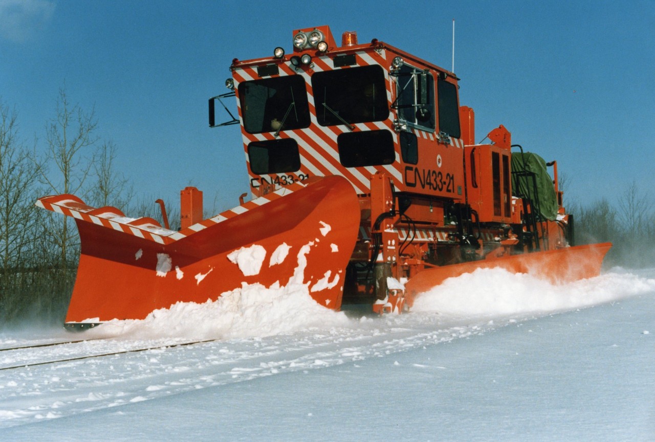 CN 433-21 is a brand new Plasser MPMV (Multi-Purpose Maintenance Vehicle), or Crew Crane Transporter (CCT), and is being mainline tested near Charny, Quebec back in December 1988. This machine concept was introduced when CN accelerated the downsizing/consolidation of section forces and utilized multi-function machines to offset the reduction in manpower. One phase of the project was known as TFM (Track Force Mechanization) and involved the development of manned camps at several remote locations in northern Ontario in the pilot project.