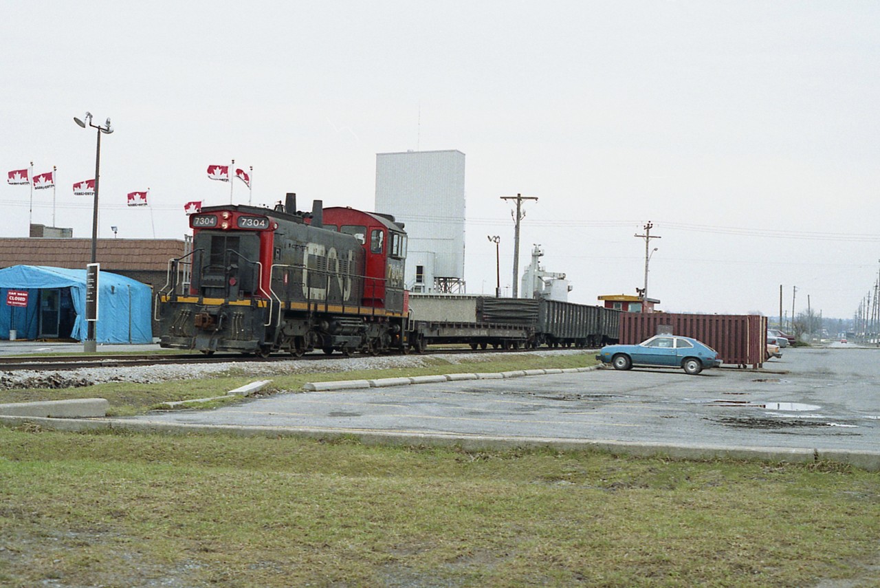 It was tough to catch anything running to Port Weller drydocks , let alone a train complete with transfer van, even it it was only 3 cars of traffic.
The boys are taking their lunch break over at Wendy's just out of sight on the right. The Petro-Can station is facing Welland Avenue, which is just behind the van in this photo looking southward.
These days, the track from under the QEW Garden City Skyway all the way to Port Weller has been taken up. The 7304 was the former CN 1390, and currently a rare bird, operating in the Industrial area of Hamilton.
Classy car parked in the lot.:o) Looks a lot like an old Pinto. But hey, this IS St. Catharines.